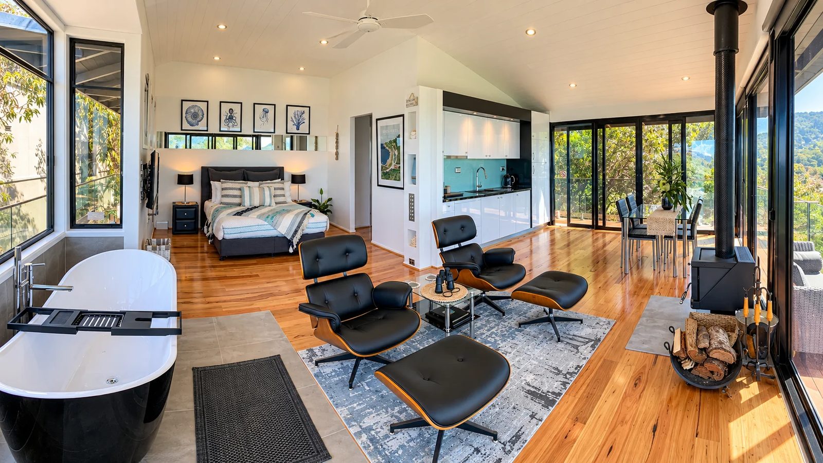 Open-plan suite at The Deck House Wye River with an oval freestanding bath, lounge chairs and fireplace